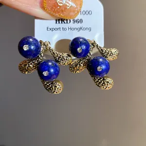 Detailed view of vintage-style earrings with blue lapis beads and gold-toned leaves.