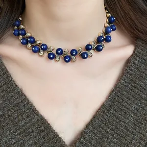 Close-up of vintage blue resin bead necklace with gold-tone leaf accents on neck