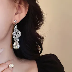 Dettaglio di orecchini pendenti con strass a goccia d'acqua su una modella elegante