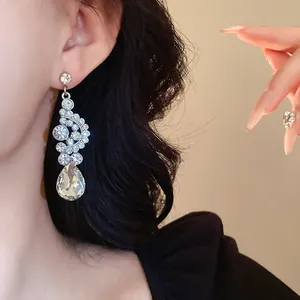 Dettaglio dell'orecchino a goccia color argento indossato da una modella elegante e raffinata