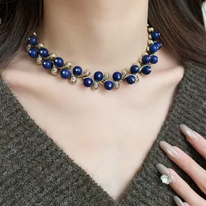 Close-up of a vintage-style gold necklace with blue resin beads and sparkling stones