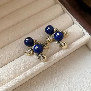 Detailed close-up of vintage style resin earrings with blue beads and textured gold base