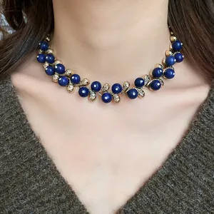 Close-up of vintage gold-tone choker necklace with deep blue resin beads on model