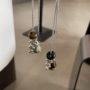 Close-up detail of natural tiger eye and dalmatian jasper teardrop pendant necklaces for women