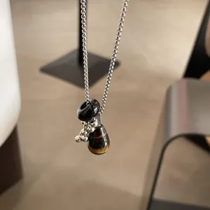 Detailed close-up of a natural tiger eye teardrop pendant on a silver ball chain necklace