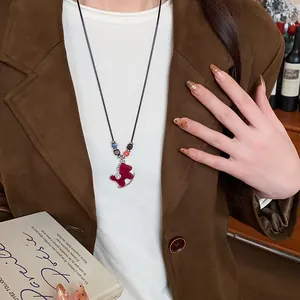 Close-up detail of red flocked rocking horse pendant necklace worn with a brown blazer