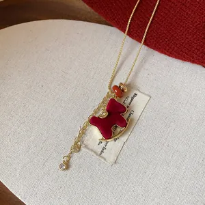 Close-up of a red flocked rocking horse necklace with golden chain and zircon details.