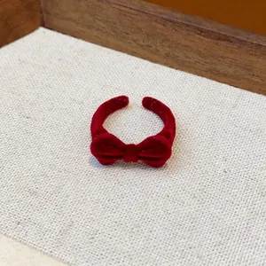 Vintage roter beflockter Schleifenring für Damen auf beigefarbenem strukturiertem Pad