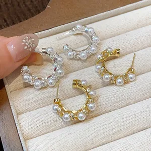 Close-up of elegant C-shaped hoop earrings with pearls and shimmering zircons