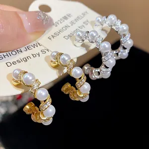 Detail of 18k gold plated hoop earrings with pearls and zircon crystals for women.