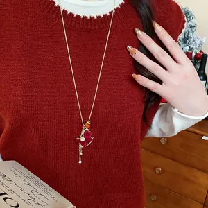 Detail view of a festive red flocked rocking horse pendant necklace on a red sweater.