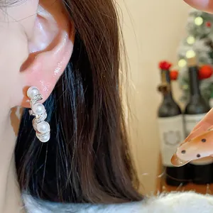 Detailed shot of elegant French style pearl and zircon drop earrings worn on a woman ear