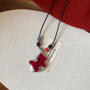 Close-up of red flocked rocking horse necklace with zircon and colorful beads details.