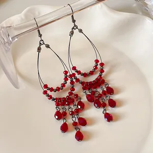 Detailed view of bohemian red glass beaded waterdrop earrings with silver hooks