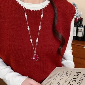 Elegant red flocked horse pendant necklace with pearls shown on a knit sweater