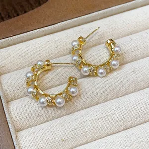 Detail view of gold-plated hoop earrings with elegant pearls and zircons