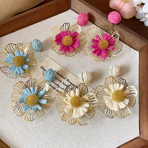 Detailansicht bunter Raffia-Blumenohrringe in einem rustikalen Holztablett präsentiert