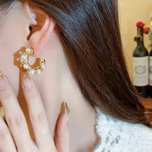 Detail view of 18k gold plated pearl and zircon hoop earring on model's ear