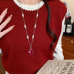 Detail view of a pearl necklace featuring a red flocked rocking horse pendant with zircon accents.