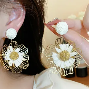 Detailansicht der handgefertigten weißen Raffia-Blumenohrringe mit Goldmetallrändern