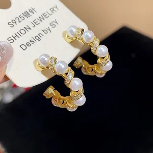 Macro view of gold plated C-shaped earrings with pearls and S925 silver needle mark
