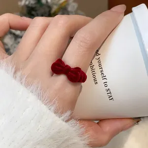 Nahaufnahme eines roten Samtbogenrings am Finger mit gemütlichem weißem Pullover
