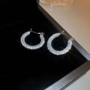 Primo piano di orecchini a cerchio in argento scintillanti con cristalli micro-pave.