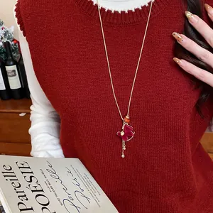 Red flocked pony sweater necklace with gold-tone chain on festive red knit