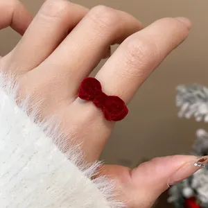 Detailansicht eines roten Vintage-Rings mit beflockter Schleife am Finger für den Winter.