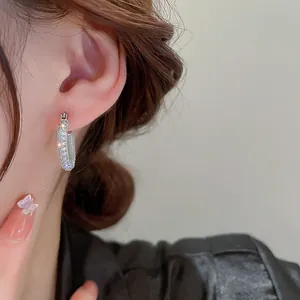 Dettaglio di eleganti orecchini a cerchio in argento con cristalli scintillanti.