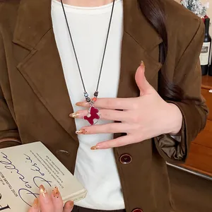 Red flocked rocking horse pendant necklace worn with a stylish brown blazer and book