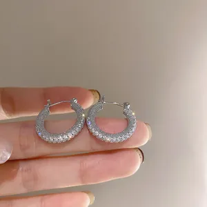 Dettaglio di orecchini a cerchio geometrici in argento con pavé di pietre di zirconia