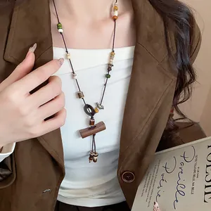 Close-up of a boho ethnic long necklace with wooden beads and ceramic pendant details.