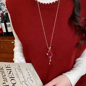 Close-up detail of a red flocked horse pendant long sweater necklace on a model