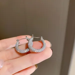 Primo piano di orecchini a cerchio geometrici in argento stile vintage con zirconi bianchi.