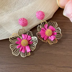 Detailansicht von rosa Raffia-Blumenohrringen mit goldenen Metallblütenblättern, Urlaubsstil