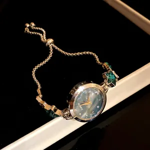 Detail of gold watch bracelet with emerald green star gems and blue marble dial