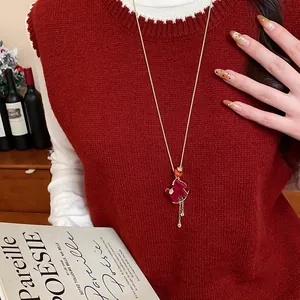 Close-up detail of a red flocked rocking horse pendant on a long gold sweater chain