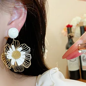 Nahaufnahme des eleganten Raffia-Blumenohrrings mit goldenen Drahtrahmen-Blütenblättern