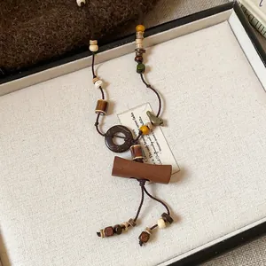 Close-up of ethnic boho long necklace with wooden and ceramic beads on white tray