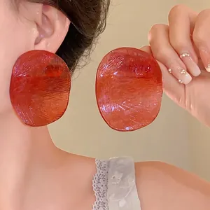 Stylish large reddish-orange resin disc earrings with textured finish