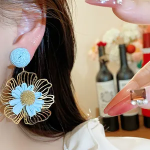 Elegante blaue Raffia- und goldene Blumenohrringe, getragen am Modell für Urlaub