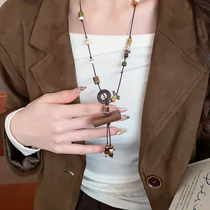 Bohemian long ethnic necklace featuring wooden beads and ceramic charms on model