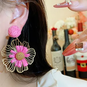Detailansicht handgefertigter pinker Bastblumenohrringe mit goldfarbenen Metallblättern