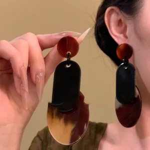 Close-up detail of oversized geometric earrings in black and brown tortoiseshell acrylic