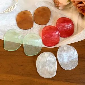 Close-up of multi-colored irregular resin earring studs on a wooden surface
