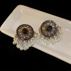Vintage ethnic style earrings with black rhinestones and pearl tassels on a white dish.