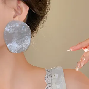 Close-up macro shot of large vintage grey prawn cracker style earring on model's ear