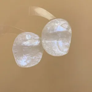 Macro detail of translucent prawn-shaped textured stud earrings with silver needles.