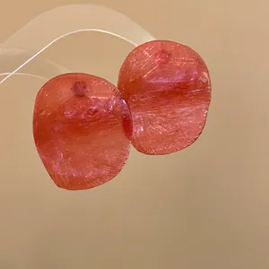 Close-up of translucent red earrings with textured shrimp cracker pattern design